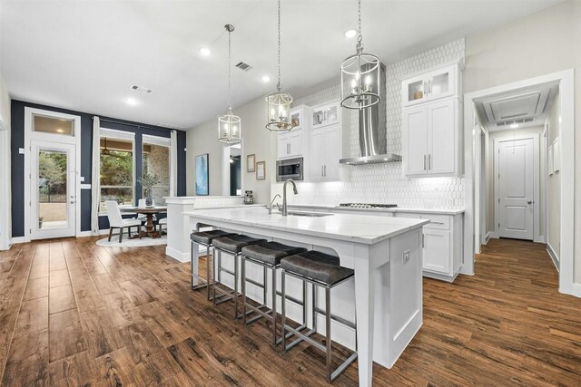 kitchen featuring light countertops, glass insert cabinets, a kitchen island with sink, white cabinetry, and a sink