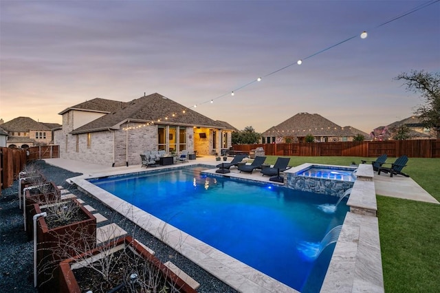 pool at dusk featuring a yard, a patio area, a fenced backyard, and a pool with connected hot tub