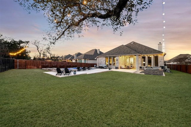 exterior space with a chimney, a patio area, a lawn, and a fenced backyard