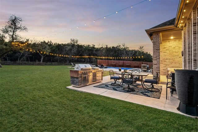 view of yard with a patio area, a fenced backyard, and an outdoor kitchen