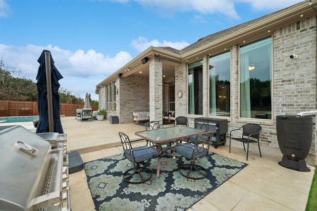 view of patio with outdoor dining area, a grill, and fence