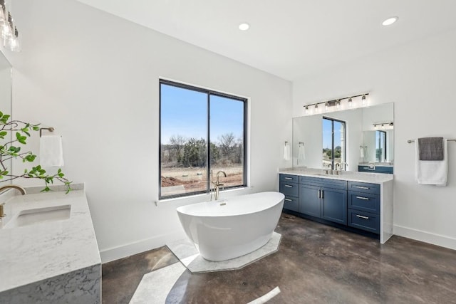 bathroom with a wealth of natural light, concrete floors, two vanities, and a sink