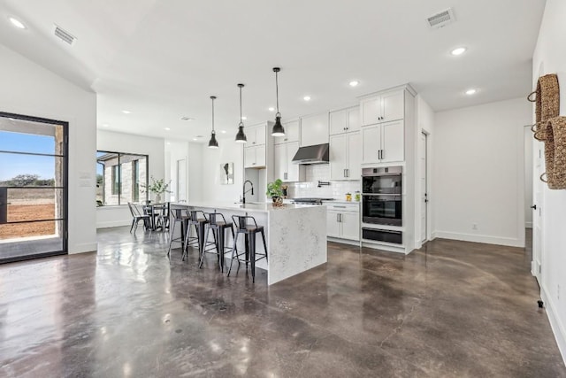 138 Cloudwood Ranch Rd, Briggs, TX 78608 - kitchen with ventilation hood, stainless steel double oven, finished concrete floors, a center island with sink, and backsplash