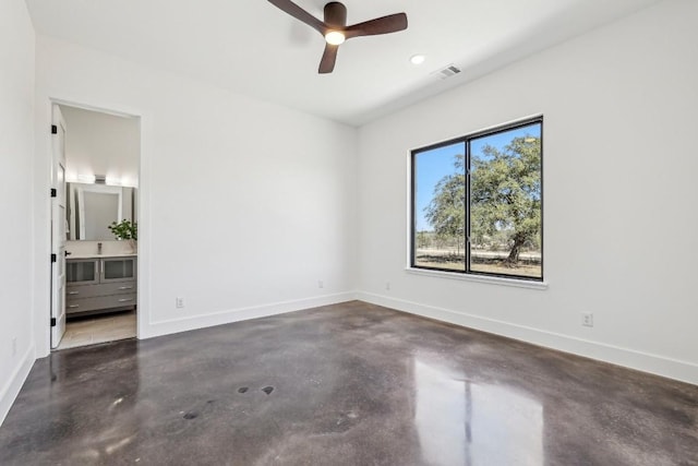 empty room with concrete flooring, a ceiling fan, visible vents, and baseboards