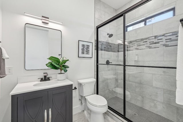 full bath with a stall shower, baseboards, vanity, and toilet