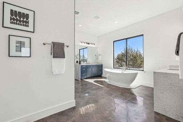 full bath featuring baseboards, a freestanding bath, vanity, concrete floors, and recessed lighting