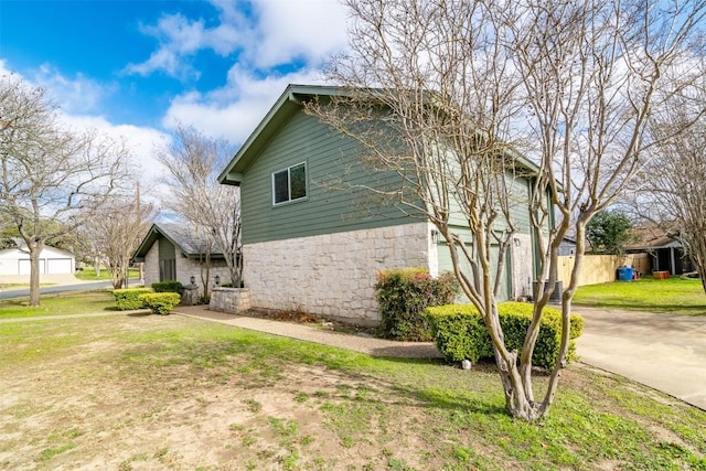 view of side of property with driveway, a yard, an attached garage, and fence