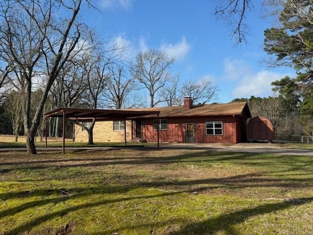 view of front facade with an outbuilding, a front lawn, a chimney, and a storage unit