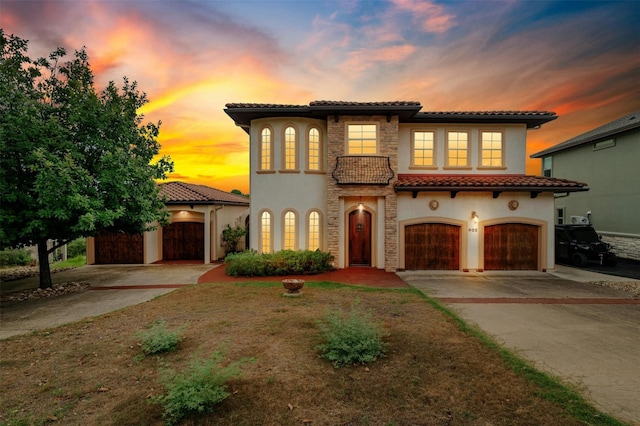 mediterranean / spanish-style home with stone siding, stucco siding, concrete driveway, and a tiled roof