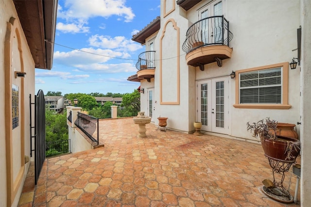 view of patio / terrace featuring french doors, fence, and a balcony