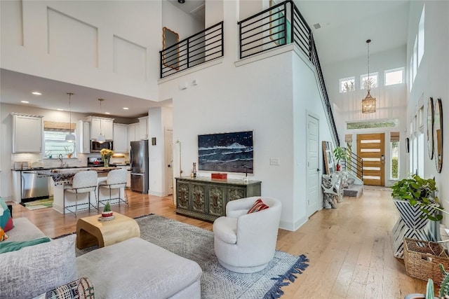 living room with light wood-style flooring, a high ceiling, and a wealth of natural light