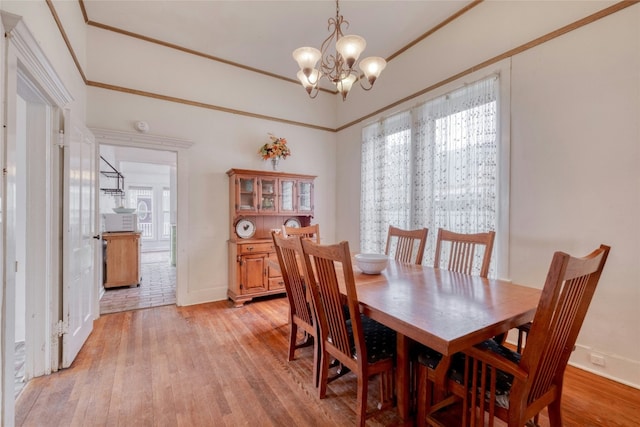 dining room with a chandelier, crown molding, light wood-style flooring, and baseboards