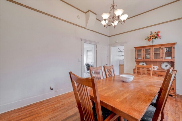 dining room with light wood-style floors, crown molding, a notable chandelier, and baseboards