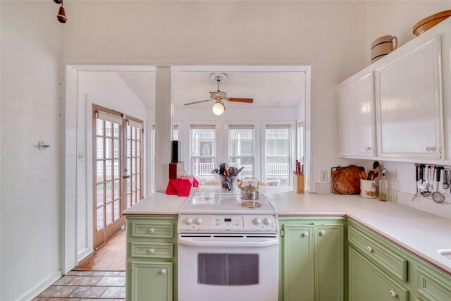 kitchen with light countertops, electric range, green cabinets, ceiling fan, and a peninsula