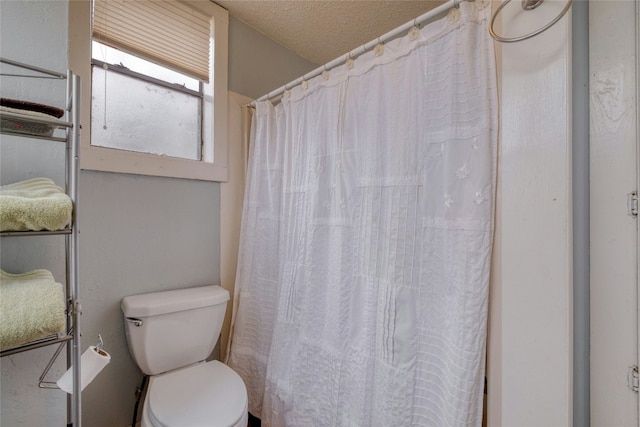 full bathroom featuring a textured ceiling and toilet