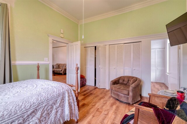 bedroom with ornamental molding, a high ceiling, and light wood-style floors