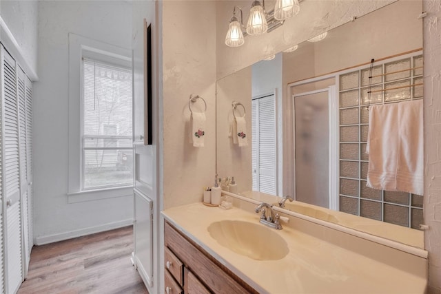full bath with a closet, vanity, baseboards, and wood finished floors