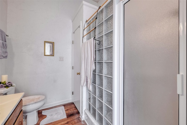 bathroom with toilet, baseboards, wood finished floors, and vanity