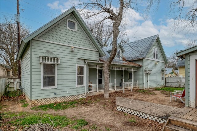 rear view of property featuring a porch and fence