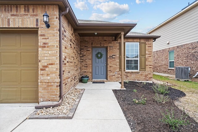 doorway to property featuring a garage, central AC, and brick siding