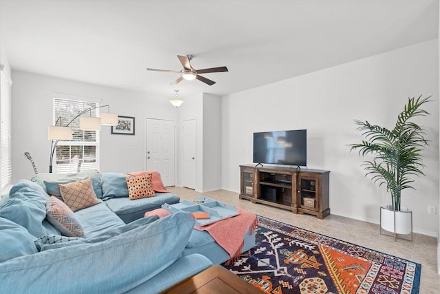 living area with ceiling fan and baseboards