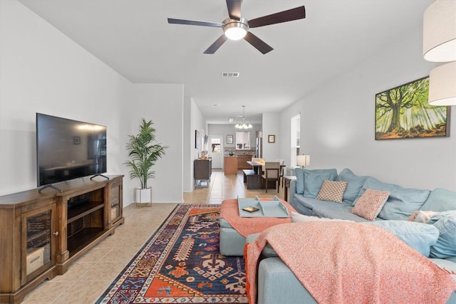 living room featuring light tile patterned floors, visible vents, and ceiling fan with notable chandelier