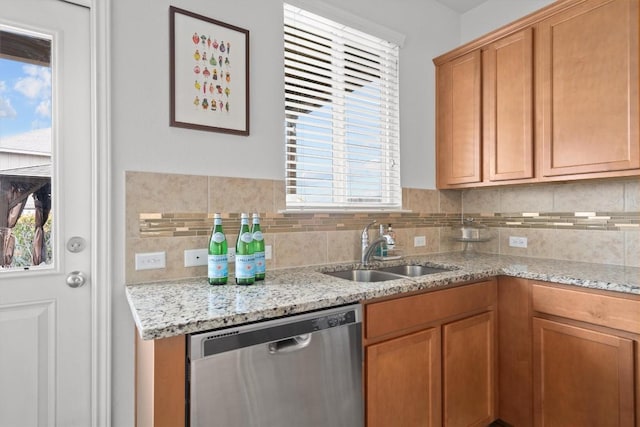 kitchen featuring a sink, light stone countertops, backsplash, and dishwasher