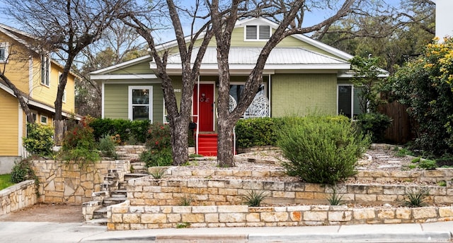 bungalow-style house featuring metal roof and brick siding