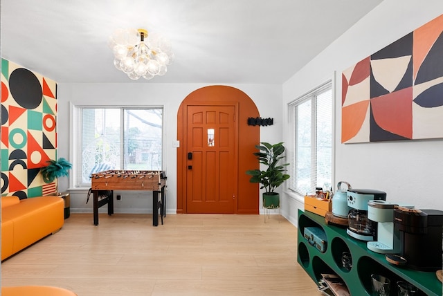 foyer entrance with a chandelier, light wood finished floors, and baseboards