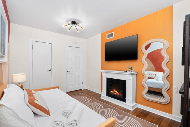902 E Live Oak St, Austin, TX 78704 - bedroom with wood finished floors, a glass covered fireplace, and baseboards