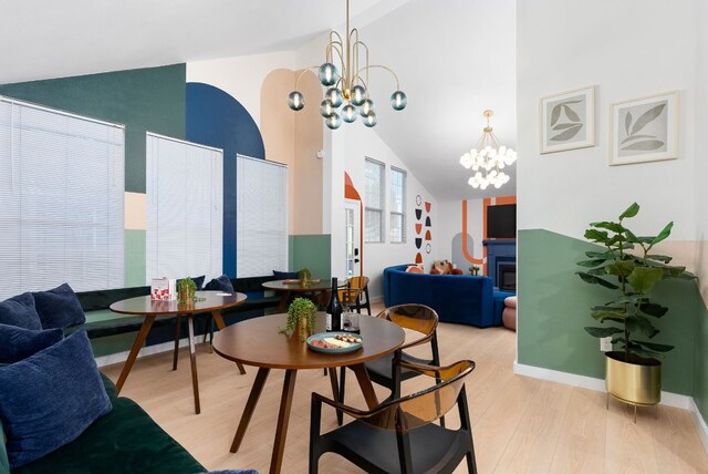 902 E Live Oak St, Austin, TX 78704 - dining space with wood finished floors, a chandelier, high vaulted ceiling, a glass covered fireplace, and baseboards