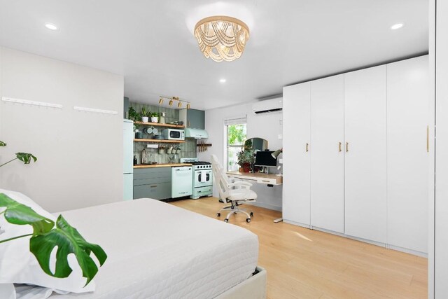 bedroom with recessed lighting, a wall mounted AC, light wood-style floors, freestanding refrigerator, and a sink