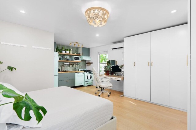 902 E Live Oak St, Austin, TX 78704 - bedroom featuring a wall mounted AC, light wood-style floors, freestanding refrigerator, an office area, and a chandelier