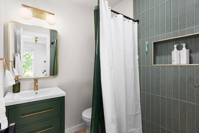 full bathroom with toilet, tiled shower, and vanity