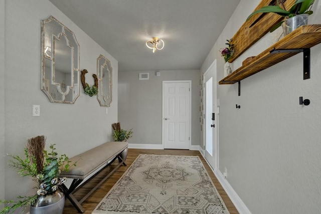 foyer entrance with visible vents, baseboards, and wood finished floors