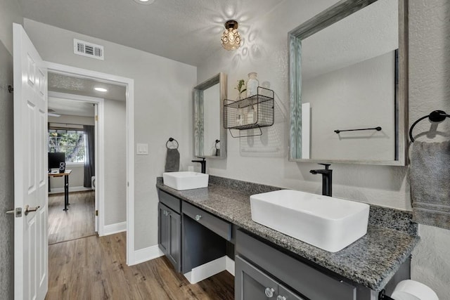 full bathroom featuring double vanity, visible vents, a sink, and wood finished floors