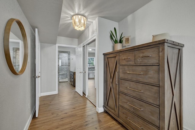 corridor featuring light wood-type flooring and baseboards