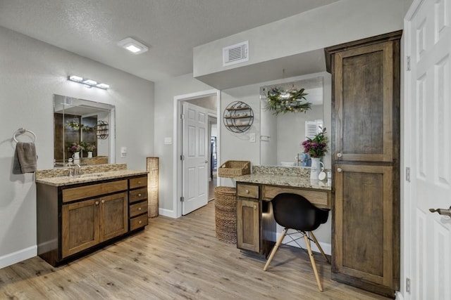 office area featuring baseboards, visible vents, a textured ceiling, light wood-style floors, and a sink