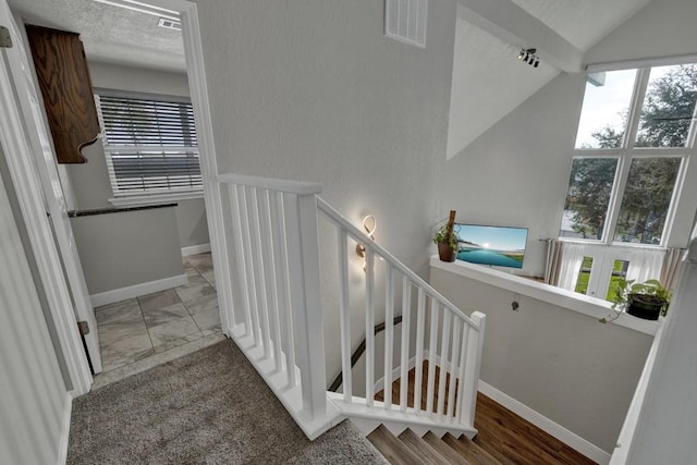 stairway featuring lofted ceiling, marble finish floor, visible vents, and baseboards