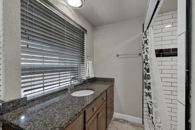 bathroom featuring marble finish floor, curtained shower, a textured ceiling, vanity, and baseboards