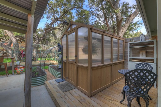 deck with a greenhouse, fence, and an outbuilding