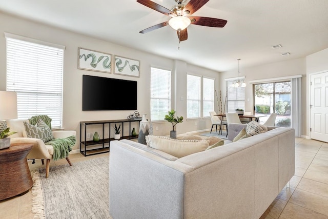 living area featuring plenty of natural light, ceiling fan with notable chandelier, baseboards, and light tile patterned flooring