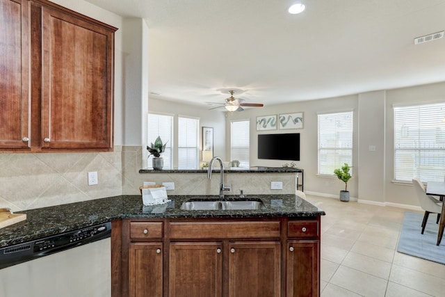 kitchen with light tile patterned flooring, a sink, visible vents, stainless steel dishwasher, and dark stone countertops