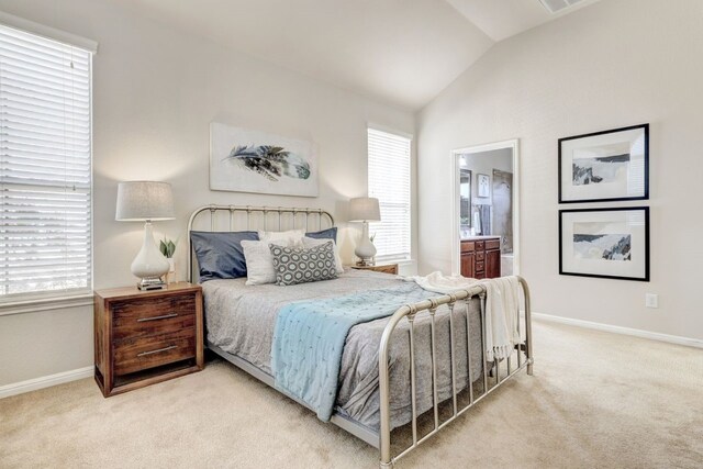 bedroom with connected bathroom, light carpet, vaulted ceiling, and baseboards