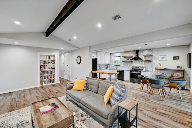 living room featuring light wood-style floors, recessed lighting, lofted ceiling with beams, and baseboards