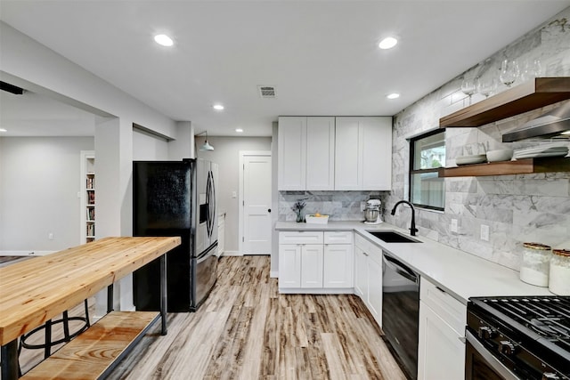 3010 Burleson Rd Unit A, Austin, TX 78741 - kitchen featuring black fridge, dishwasher, white cabinets, light countertops, and light wood finished floors
