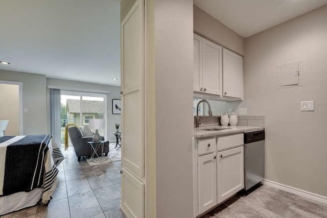 bar with a sink, baseboards, stainless steel dishwasher, and light tile patterned flooring