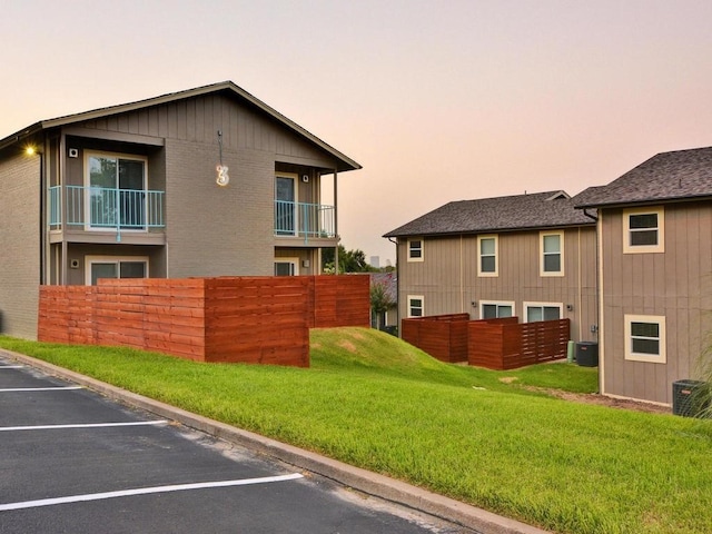 exterior space featuring a yard, uncovered parking, brick siding, and central AC unit