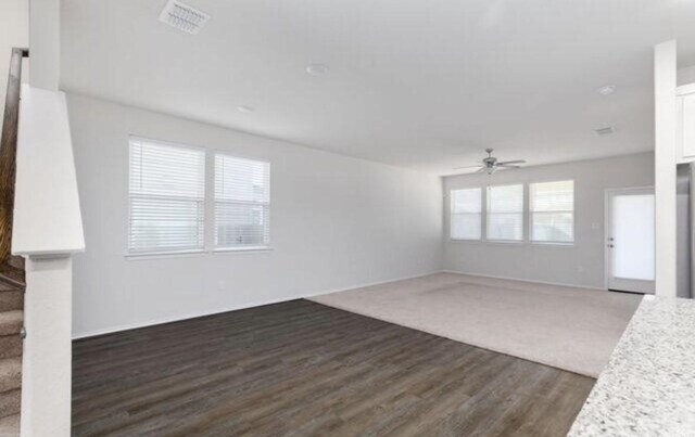 unfurnished living room with dark wood-style floors, stairway, and a ceiling fan