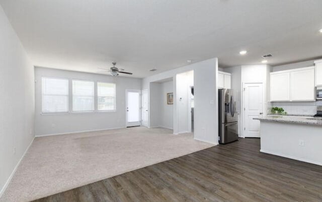 interior space with stainless steel appliances, open floor plan, white cabinetry, and visible vents